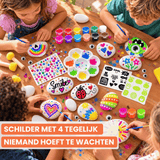 Vier kinderen schilderen samen stenen aan tafel met het Napi knutselpakket stenen schilderen