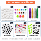 Overzicht van de 80 onderdelen: 16 witte stenen, 15 kleuren verf, glitterlijm, wiebeloogjes en stickers